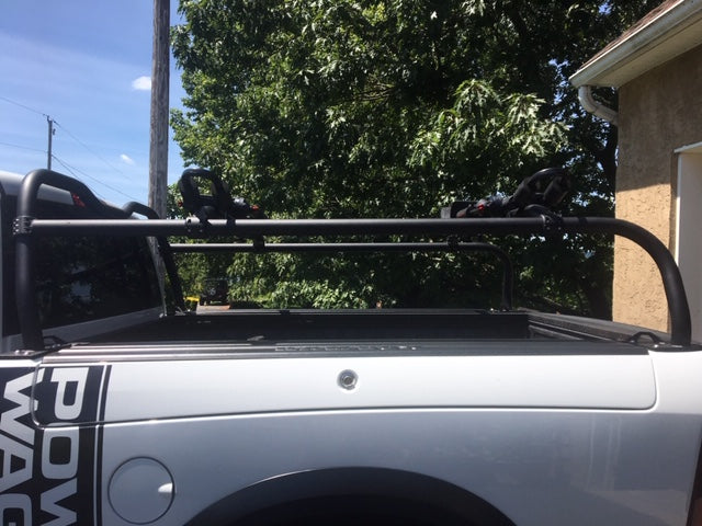 Close view along the bedside of a white Power Wagon, crossbar and side rail above a tonneau