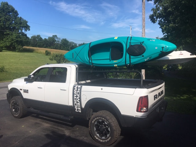 Side view of the white Power Wagon with a teal kayak and a paddleboard loaded on the rack