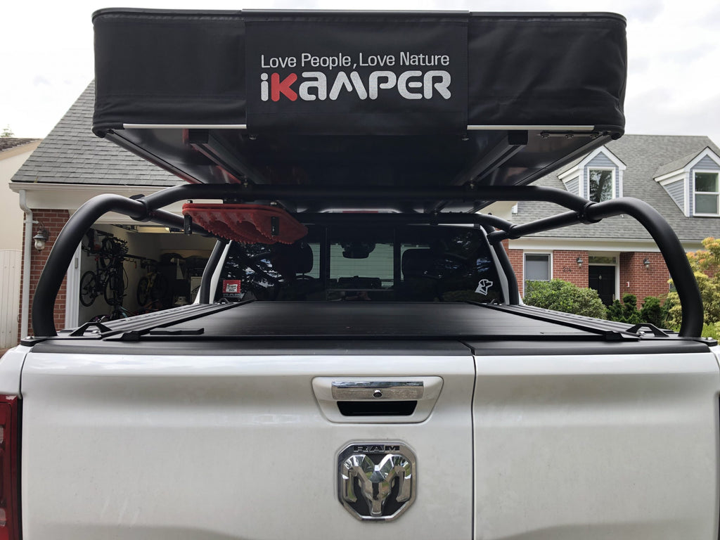 Rear view of a silver Ram with a closed roof tent mounted on the crossbars