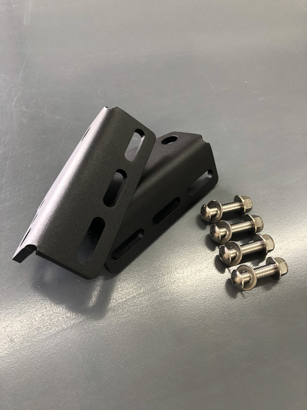 Two brackets standing on the bench with four bolts alongside