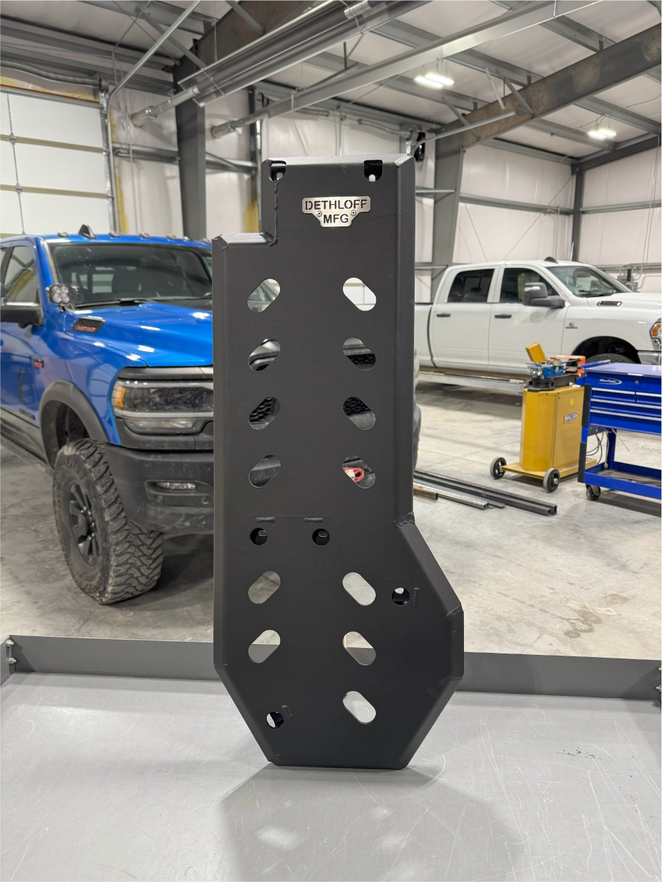 The guard upright on the bench, a blue Ram and a white Ram in the shop behind it