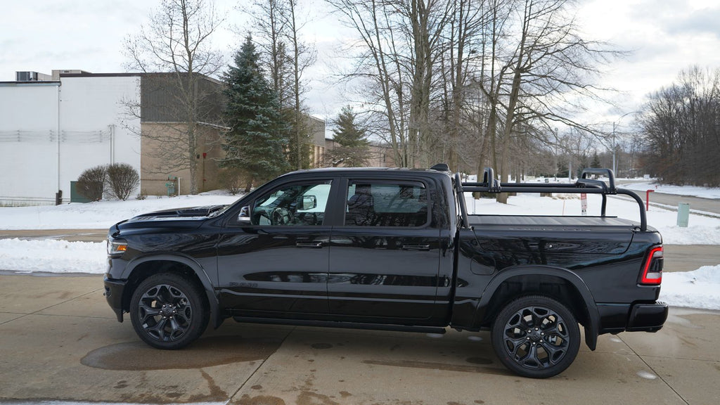 Side view of the black Ram 1500 on a snowy lot, rack and crossbars low over the bed