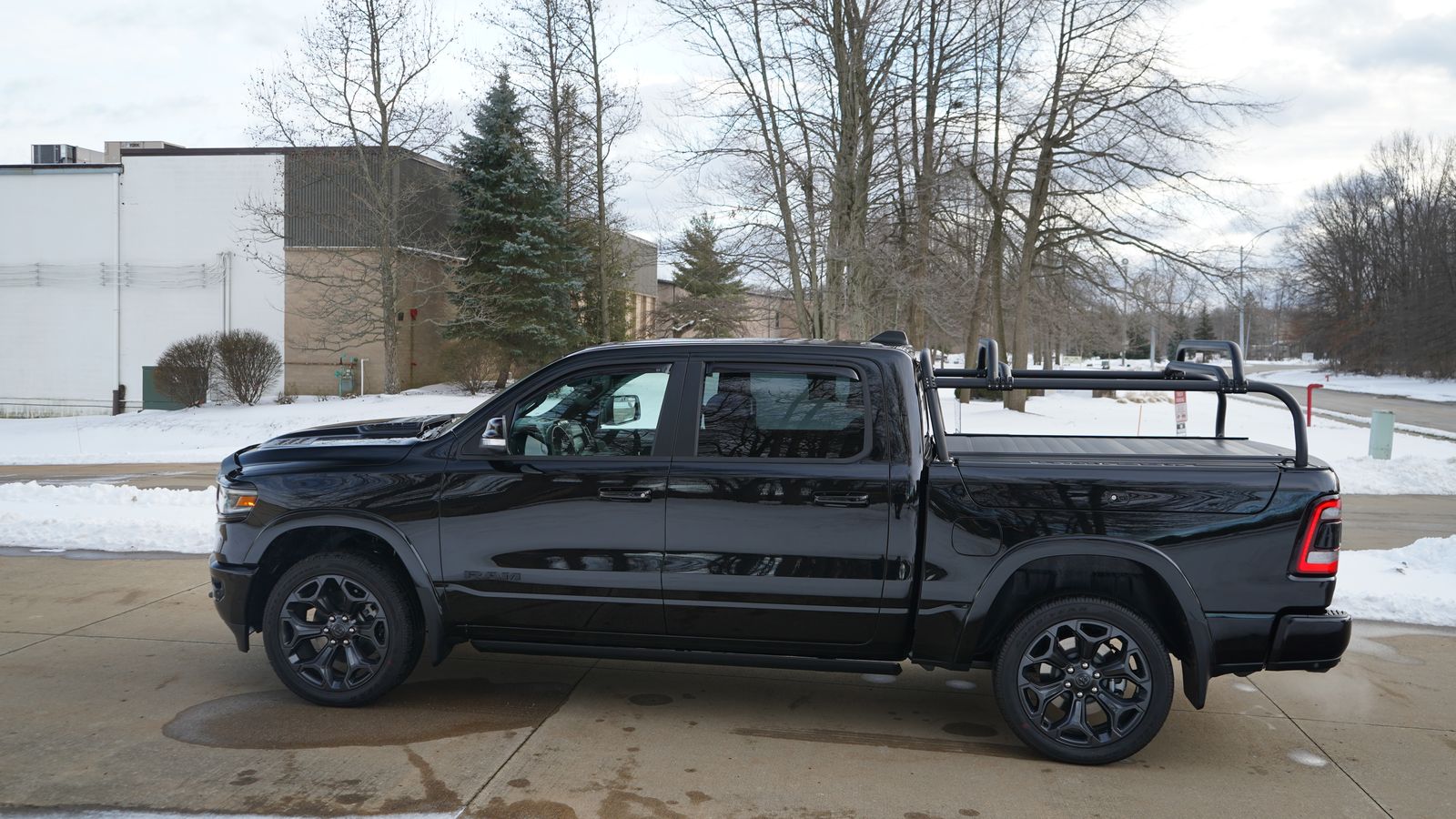Side view of the black Ram 1500 on a snowy lot, rack and crossbars low over the bed