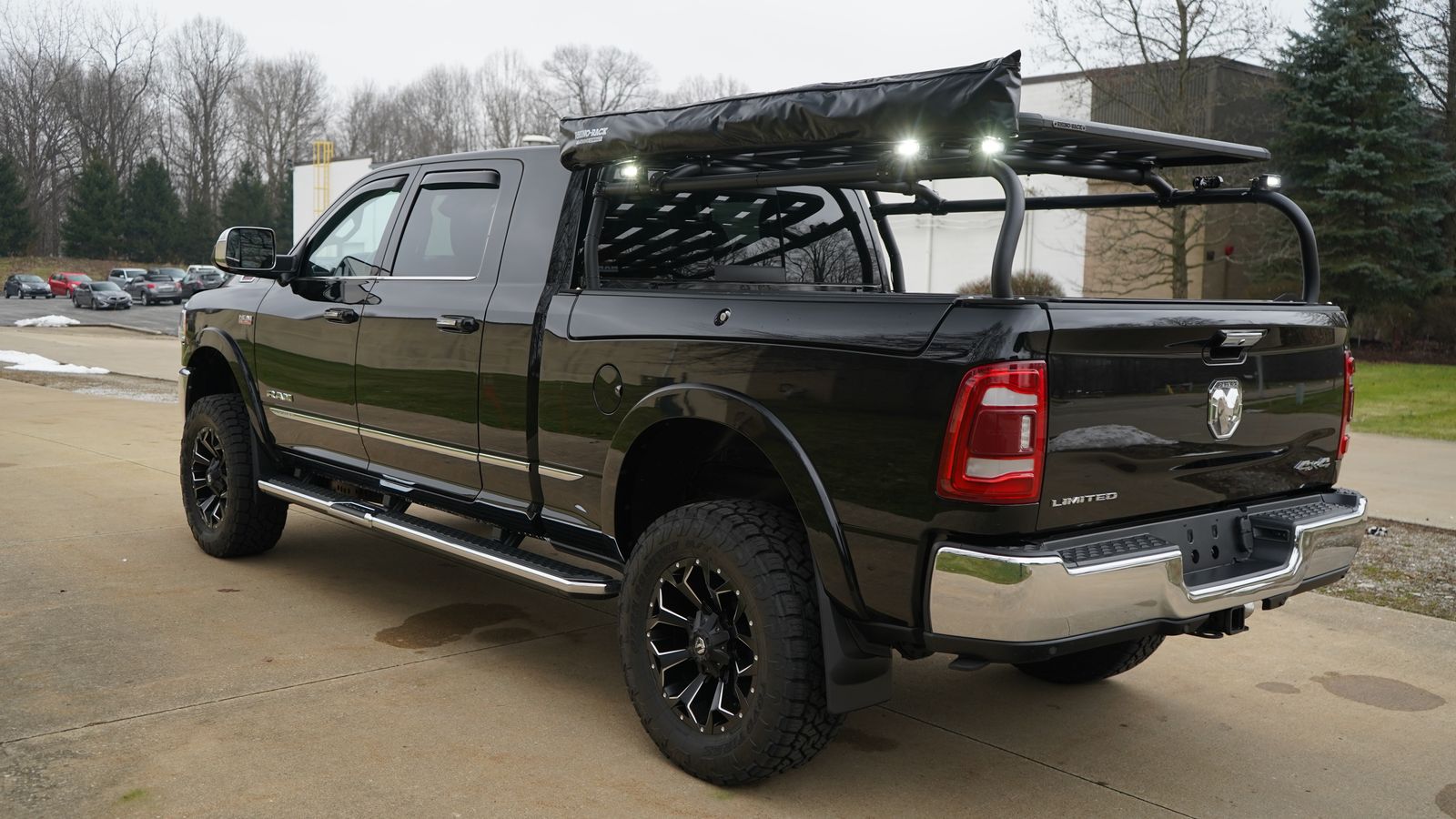 Side and rear view of the black Ram, rack lights lit and a tonneau beneath
