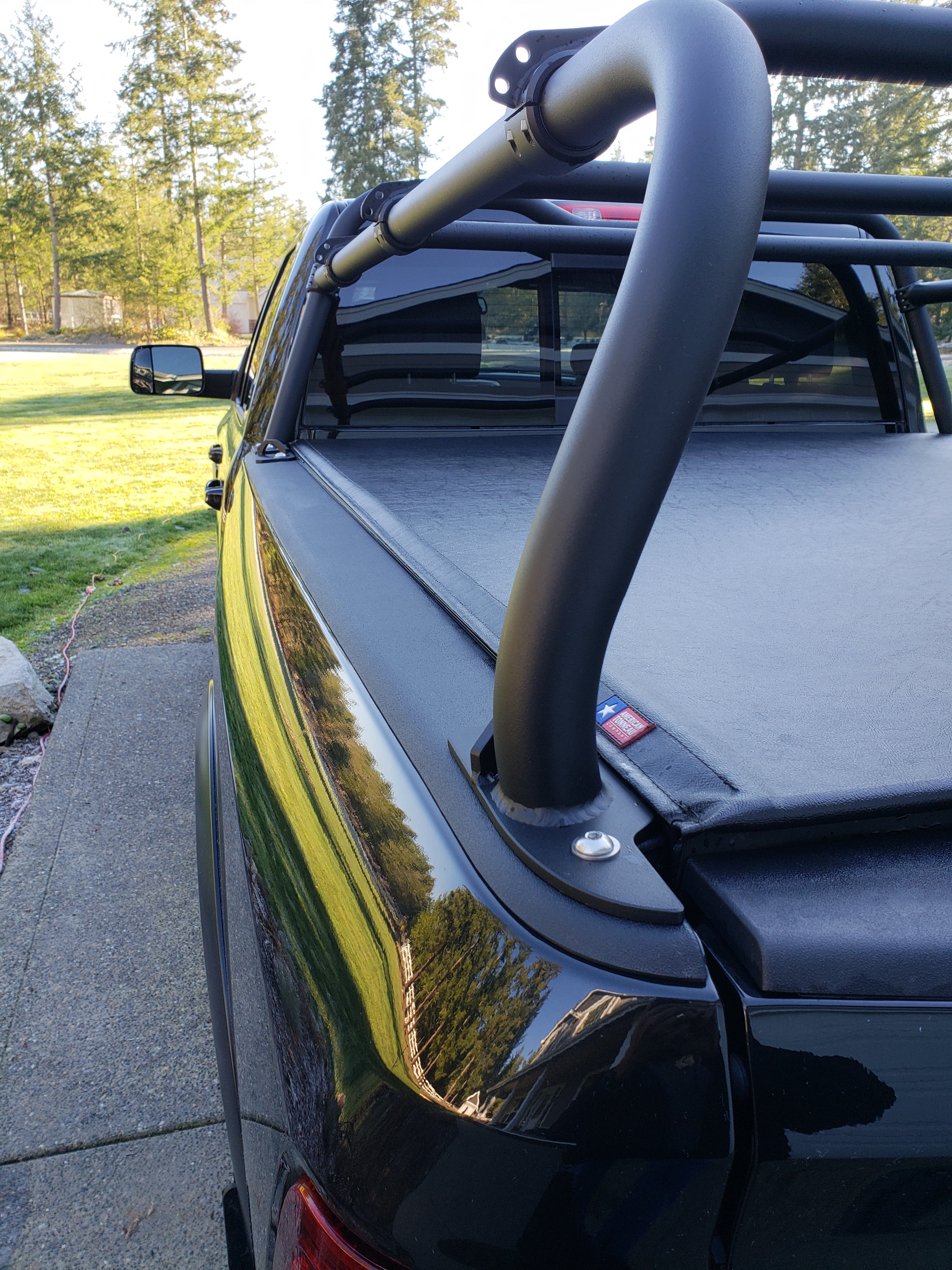 The rack's front hoop and side rail on a green truck, tonneau closed beneath