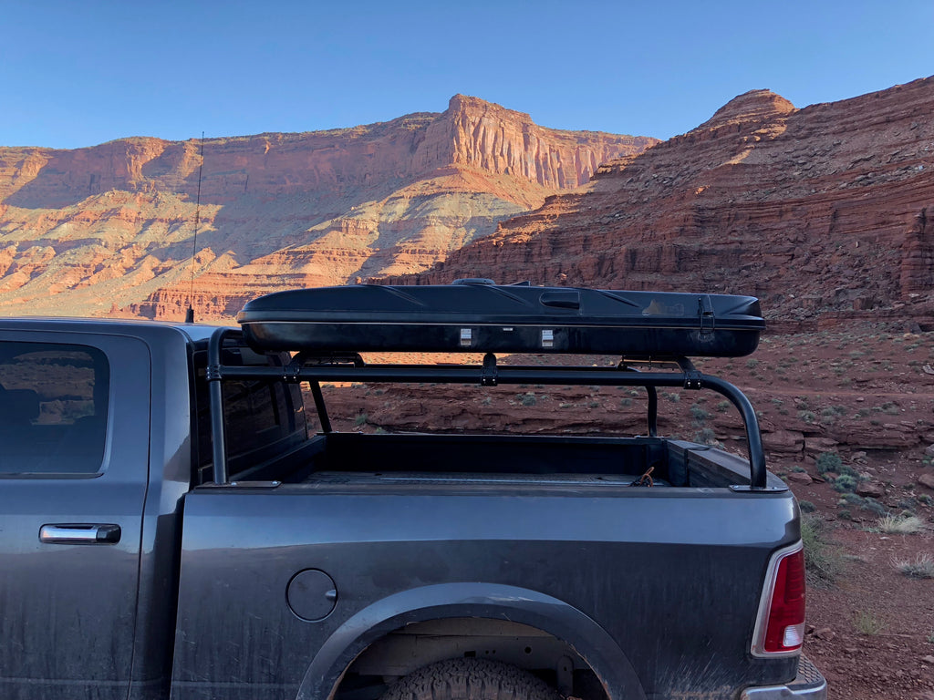 Side view of the grey Ram with the roof box carried high on the rack