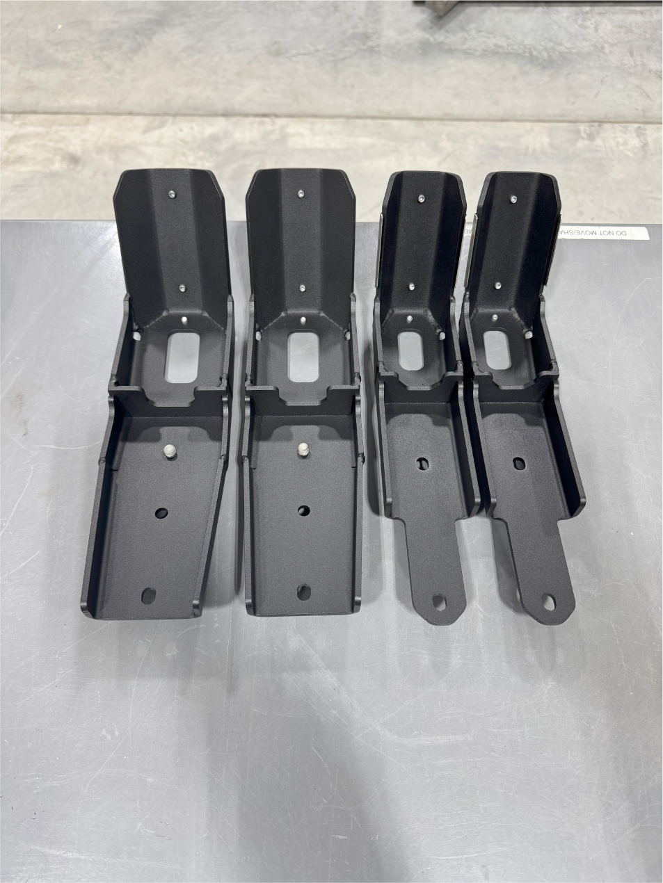 Four guards laid out on a steel bench with their clamp cutouts facing up