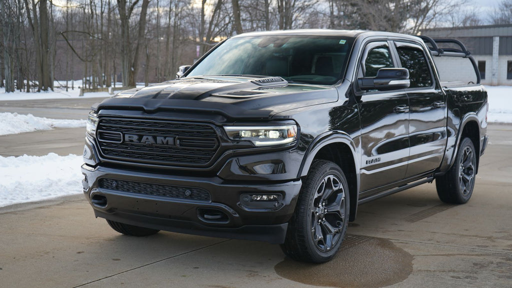 Front quarter of a black Ram 1500 on a snowy lot, rack standing above the bed