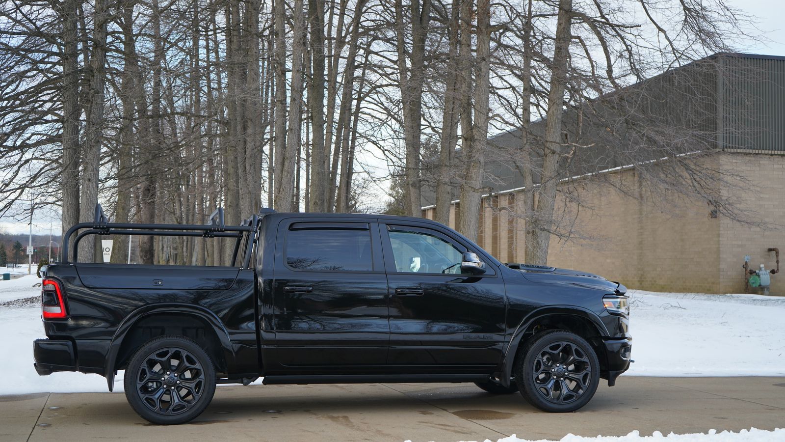 Side view of the black Ram 1500 on a snowy lot with the rack fitted