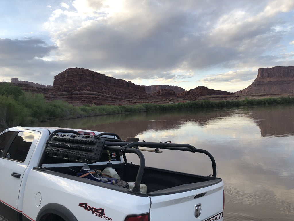 White Ram parked by a desert river, crossbars carrying gear above the bed