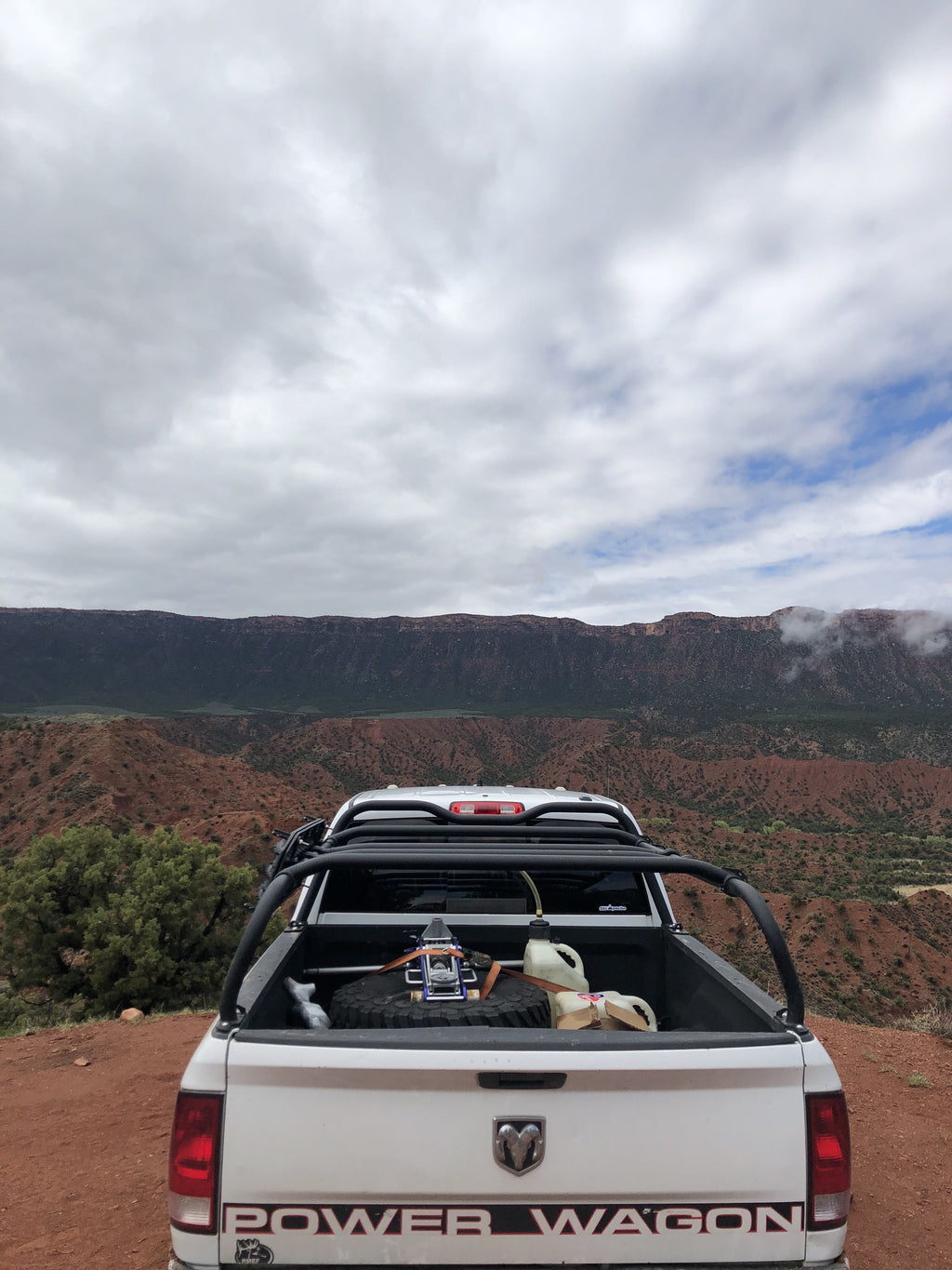 White Power Wagon on a red dirt overlook, a dog sitting in the bed under the rack