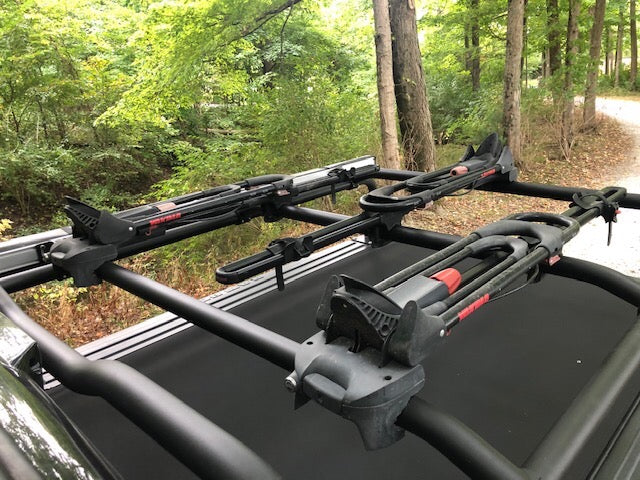Looking down at three bike carriers clamped along the crossbars over a closed tonneau