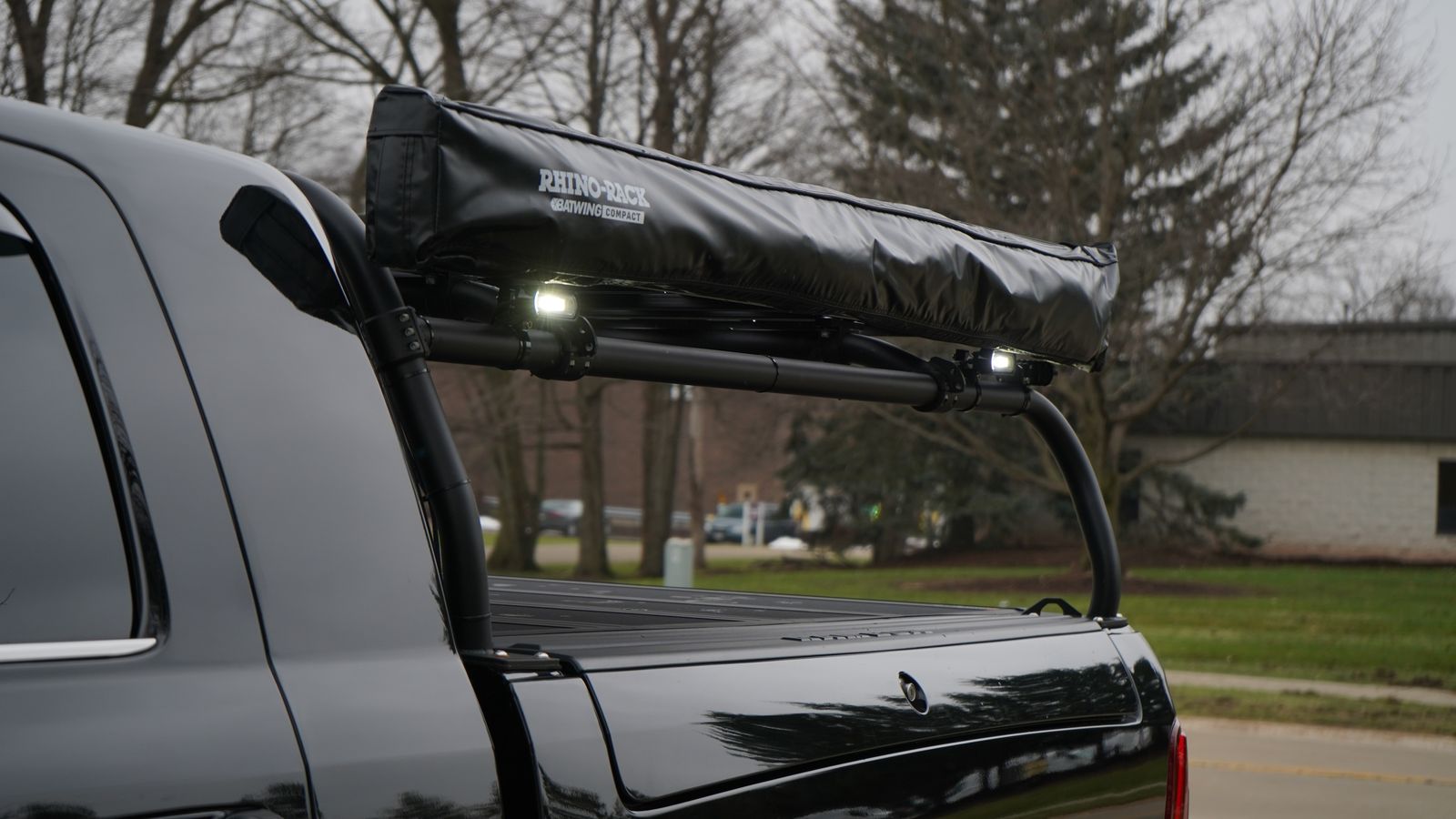 Close view of a rolled awning in its cover strapped along the rack's side rail