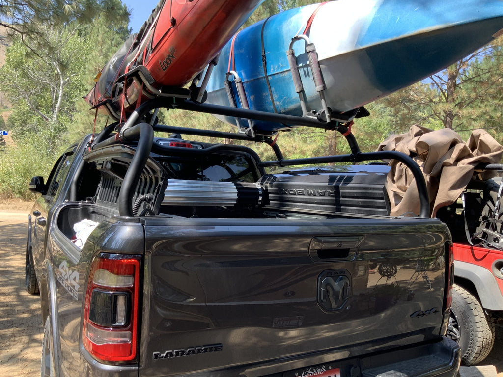 Kayaks and a cargo box loaded on the crossbars, seen from behind at a desert camp