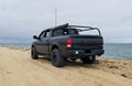 Black Ram parked on a beach at the water's edge, rack fitted over the bed