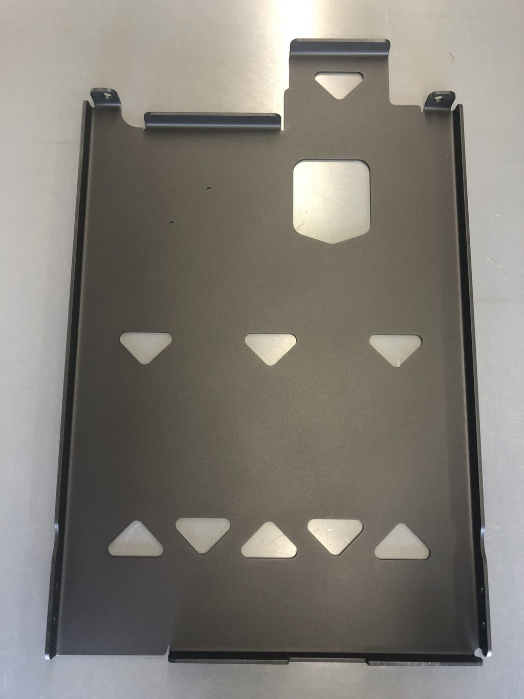 The bare plate from above on a white surface, triangular lightening cutouts across it