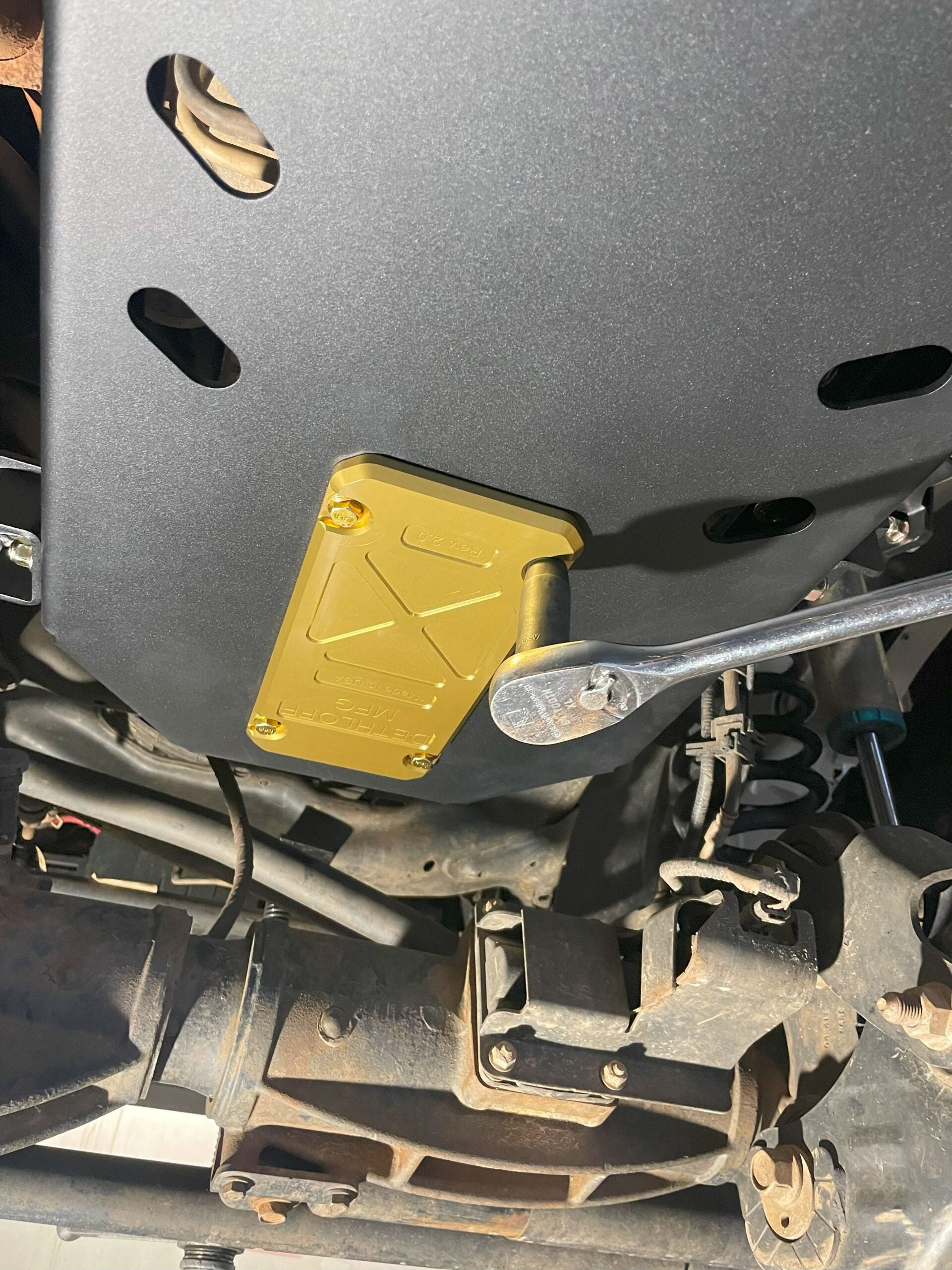A ratchet on the bolts of the gold service panel with the plate still on the truck