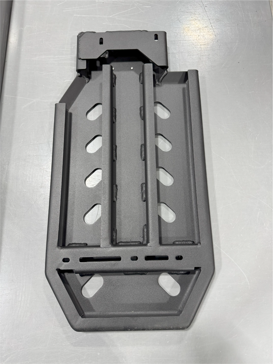 Back of the guard on a white surface, showing the ribbed stiffeners and the mounting bracket