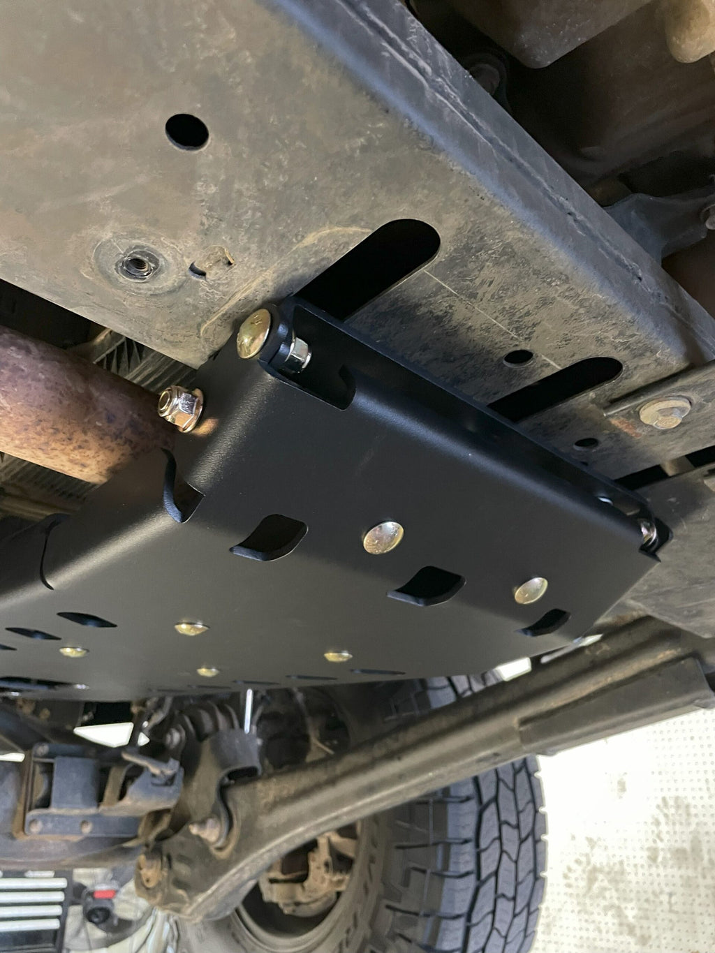 Rear edge of the plate and its bracket bolted to the frame crossmember