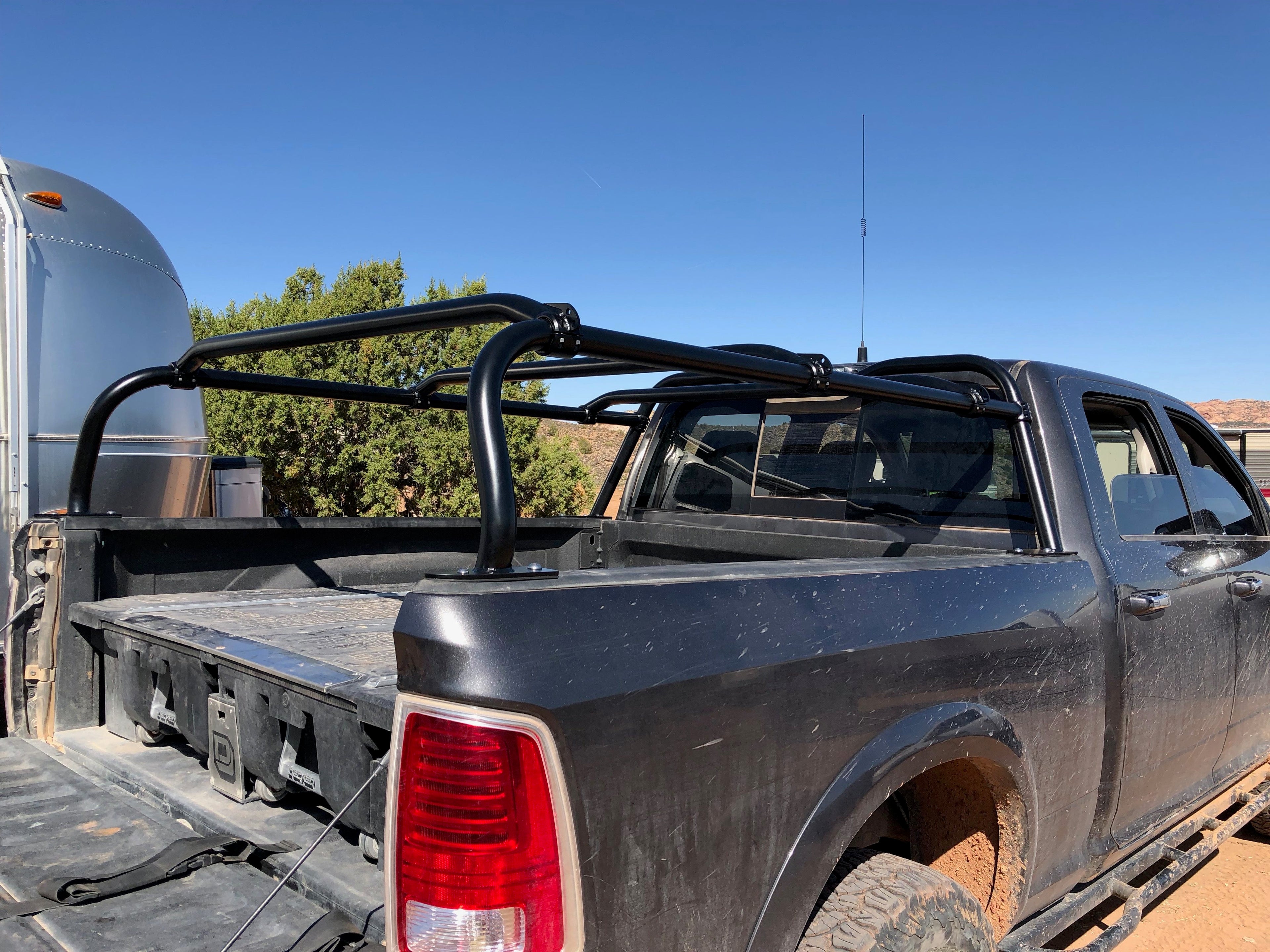 Grey Ram beside an Airstream in the desert, dust-covered bed and an empty rack