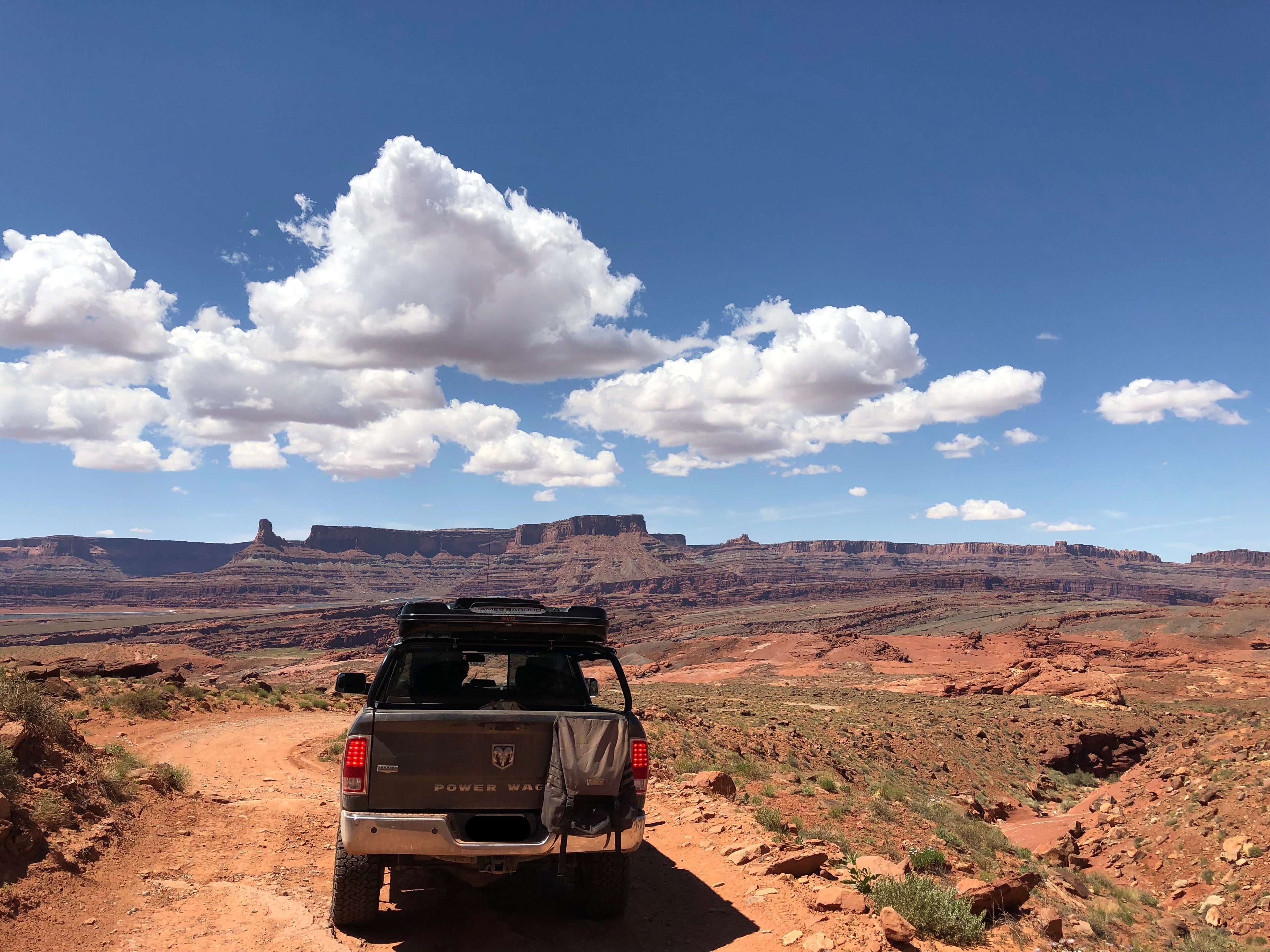 The Power Wagon on a narrow rim road above a canyon under towering clouds