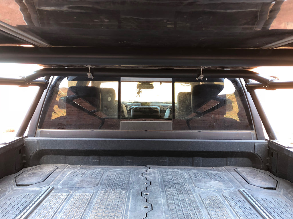 Looking forward through the bed from the tailgate, rack rails overhead and the cab window ahead