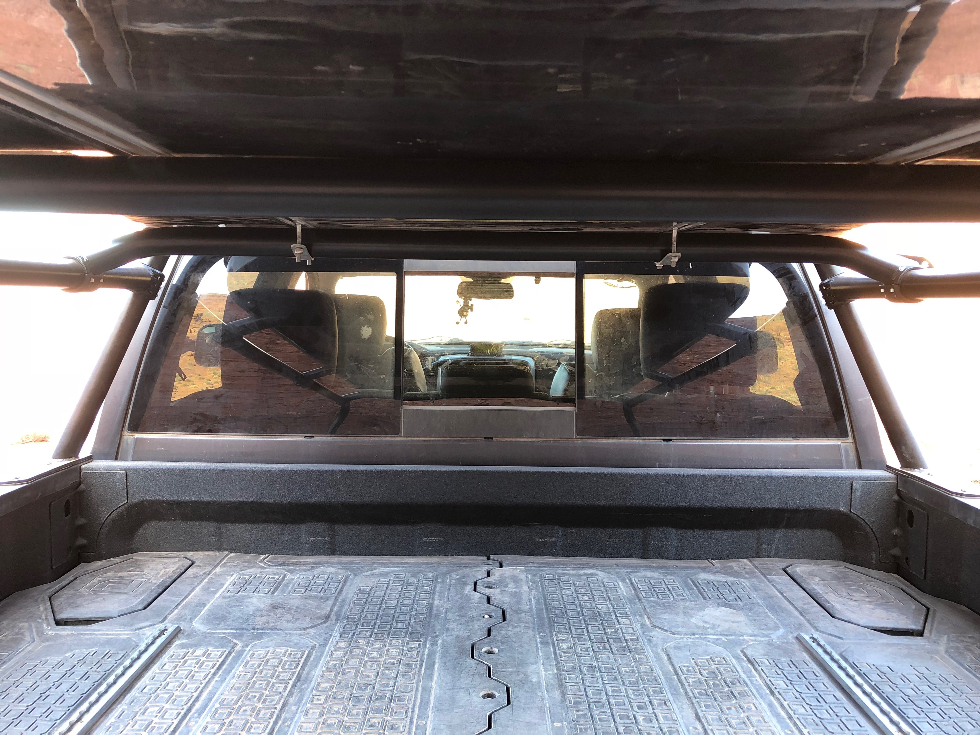 Looking forward through the bed from the tailgate, rack rails overhead and the cab window ahead
