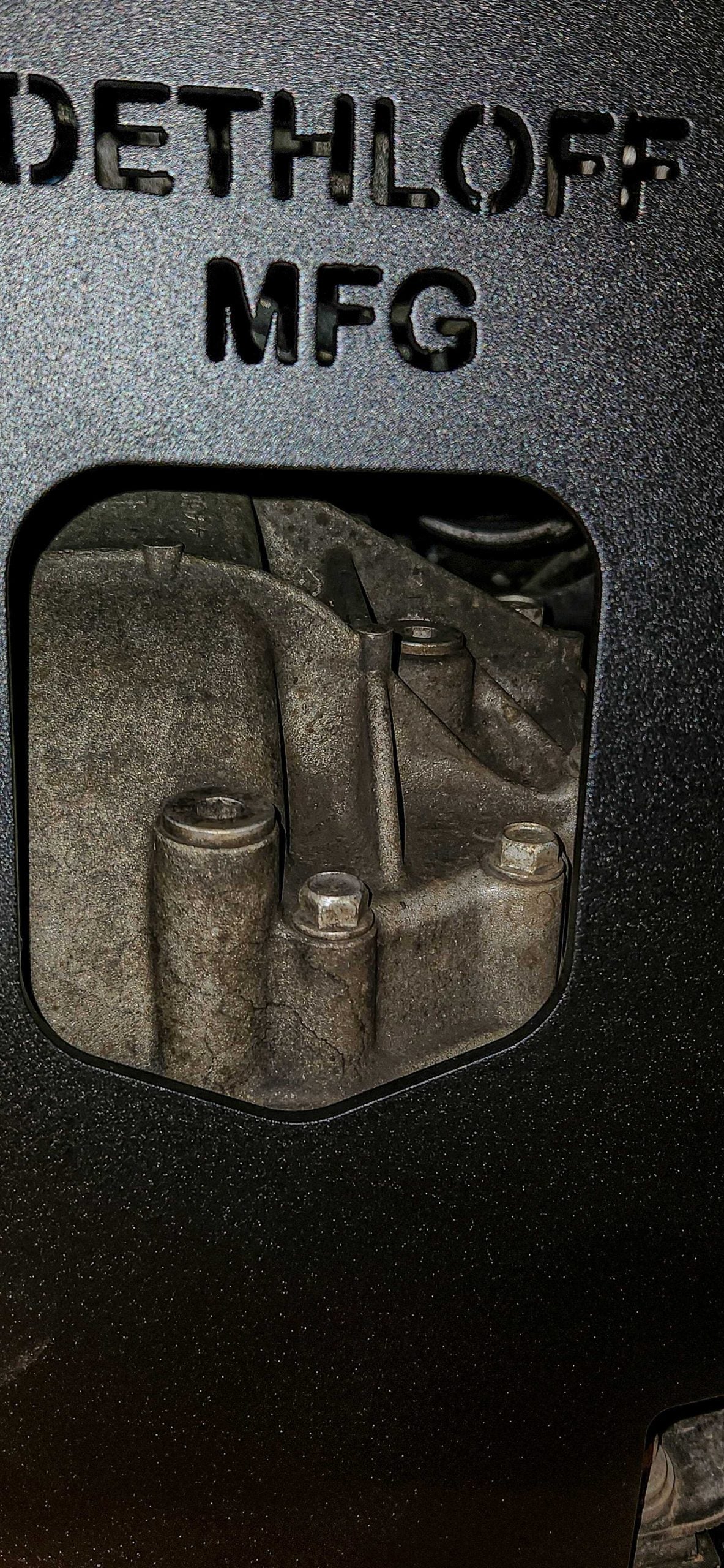 Close view of a cutout in the plate framing the differential housing behind it