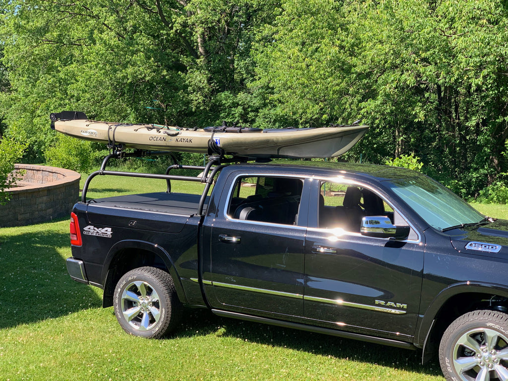 Dark blue Ram 1500 on a lawn, a sea kayak carried overhead on the rack