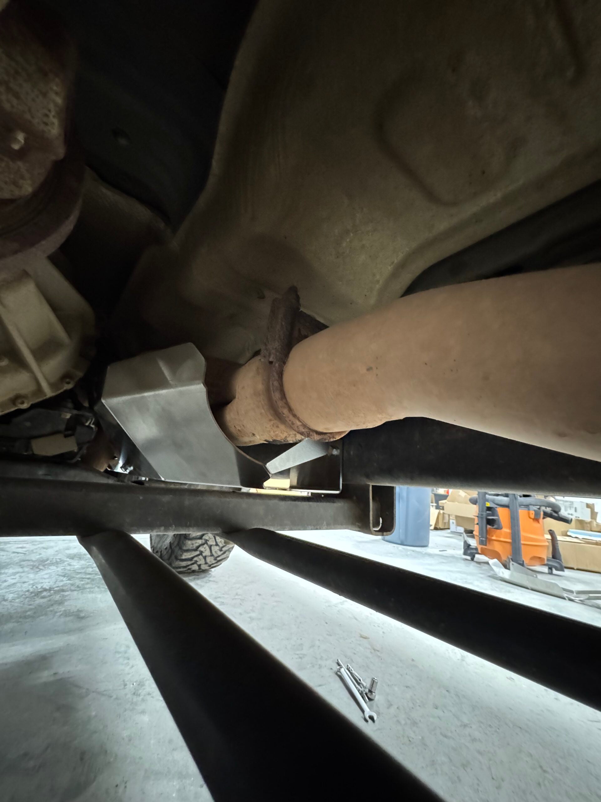 Close view of the guard wrapping around the exhaust pipe where it leaves the converter