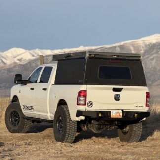 Rear three-quarter view of a white Ram HD on open grassland with snow-capped peaks behind