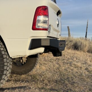 Rear corner of a white Ram, the bumper wing tucked up under the bedside and well clear of the tire