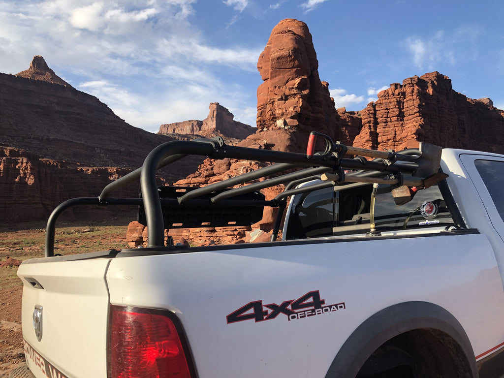 Rear quarter of a white Ram in red rock country, gear strapped along the rack