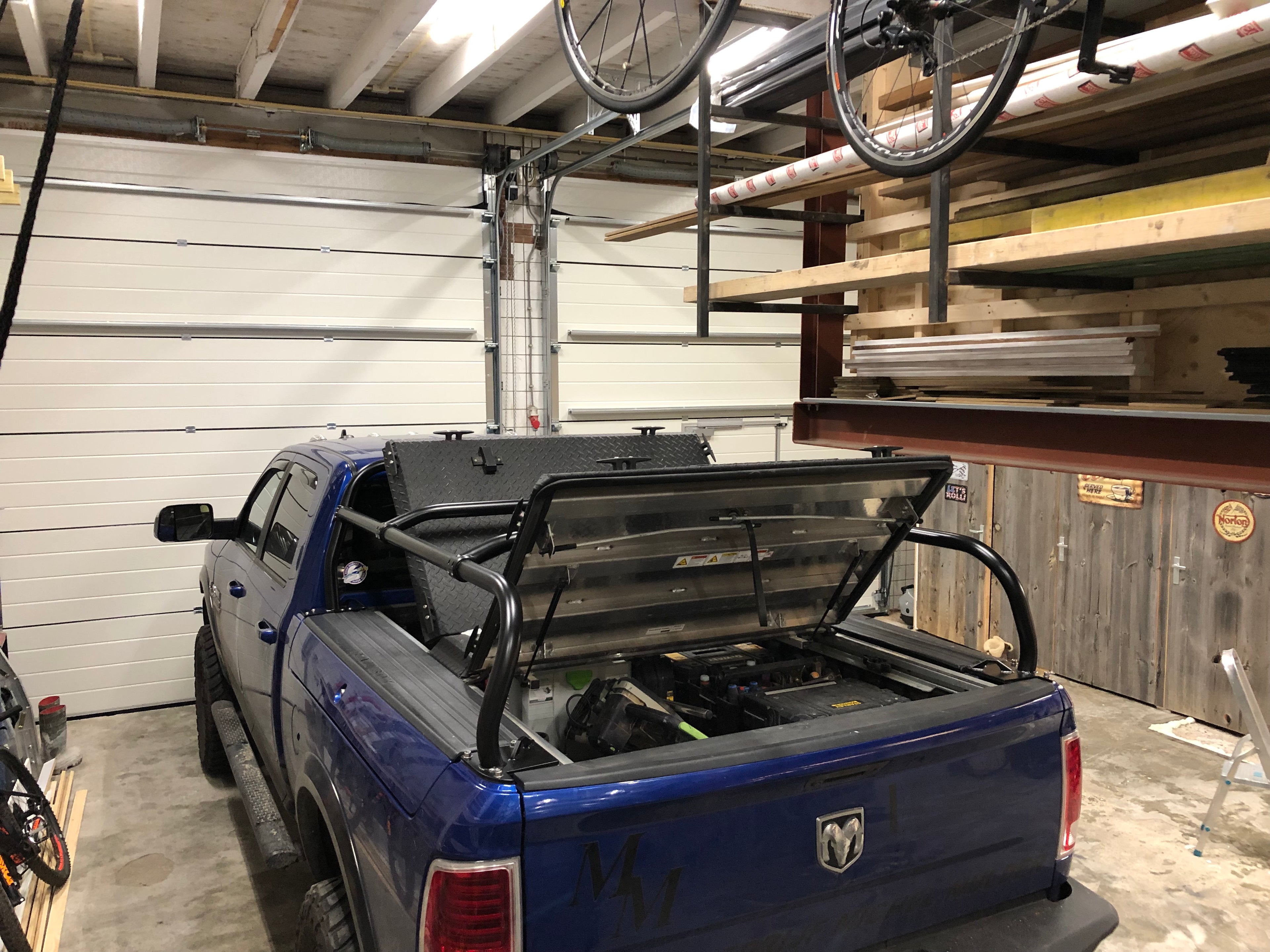 Blue Ram in a garage with the tonneau cover propped open inside the rack