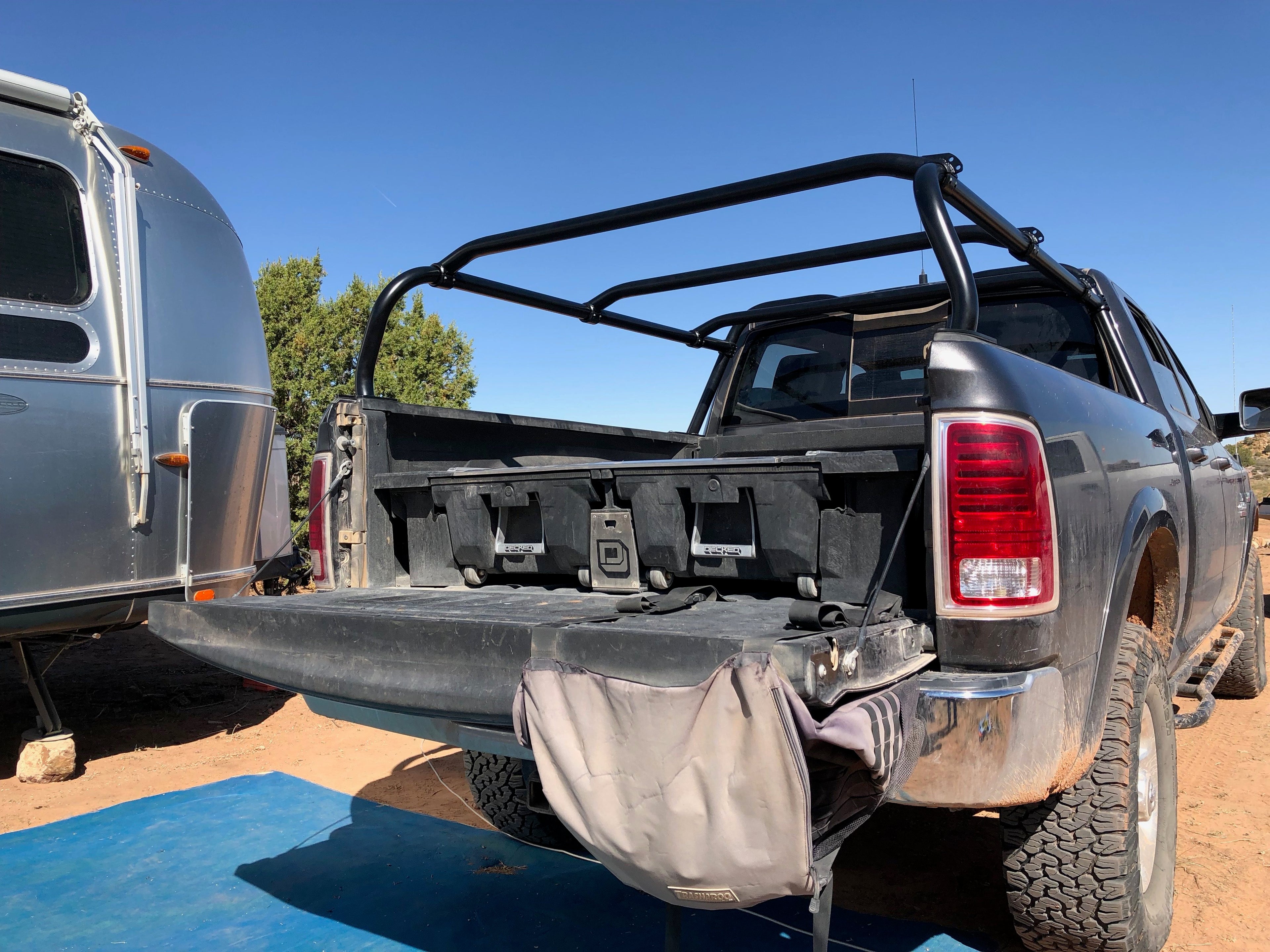 Rear quarter of a grey Ram beside an Airstream, empty rack over the bed