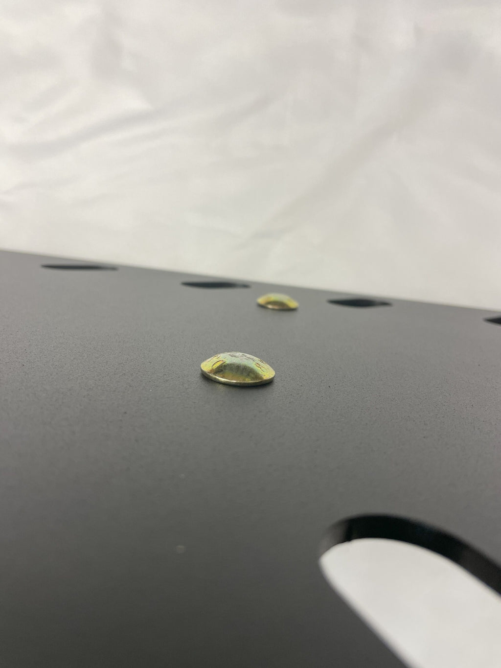 Close view of the plate surface with a gold drain plug and slotted drain openings