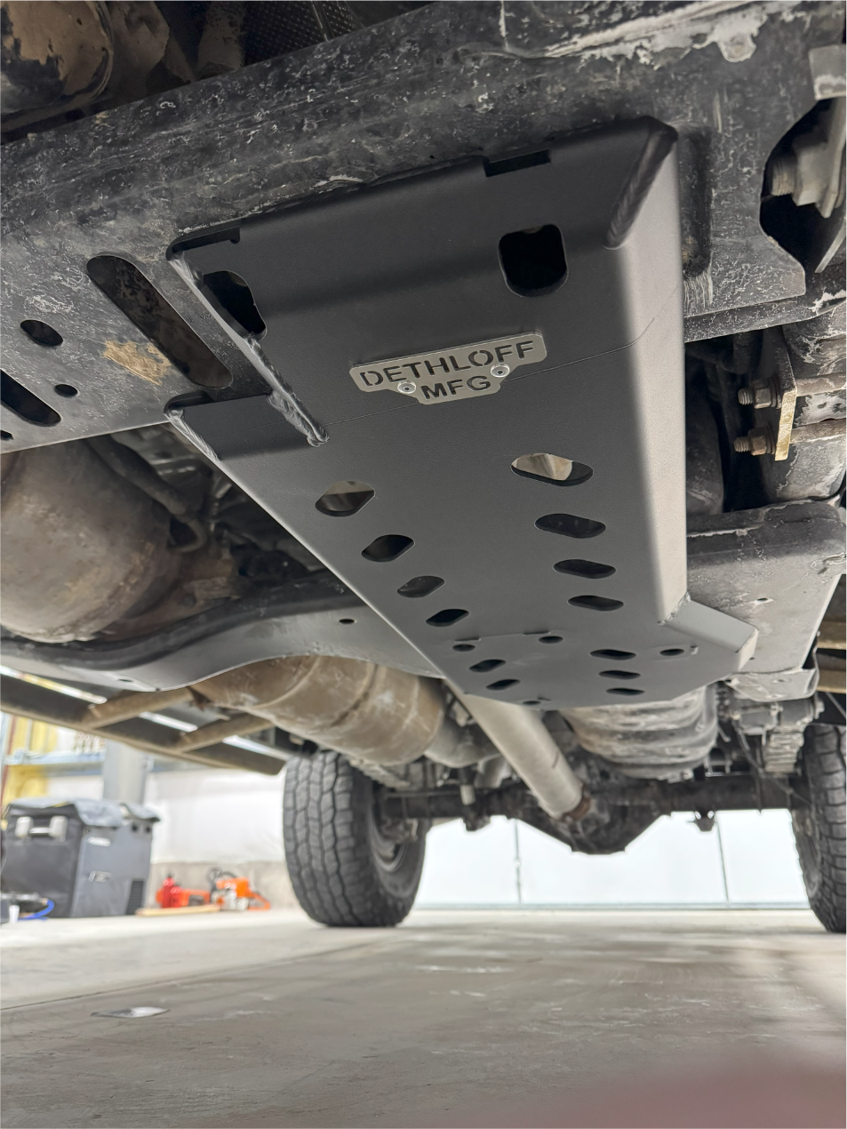 The fitted guard under the truck, seen from the shop floor with the wheel beyond