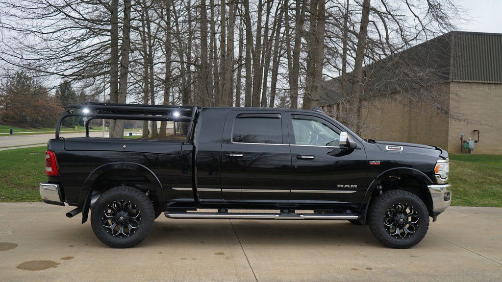 Side profile of the black Ram on a driveway, rack lights aimed forward over the cab