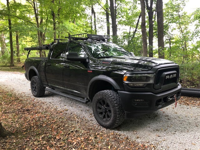 Front quarter of the black Power Wagon in the woods, basket and lights on the rack