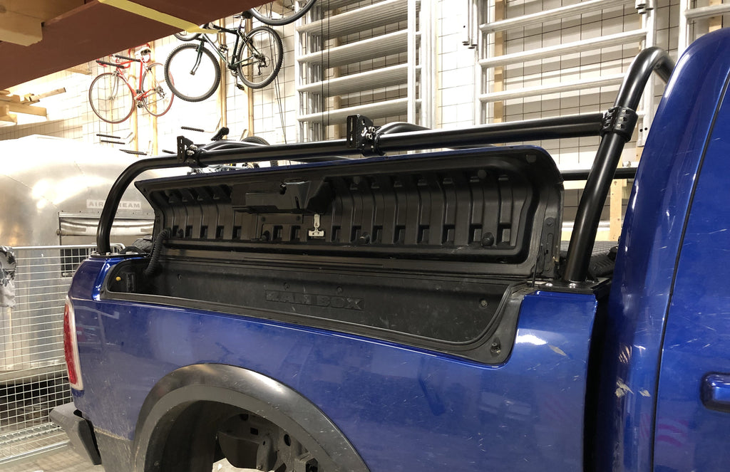 Rear quarter of the blue Ram with the tonneau folded up against the rack
