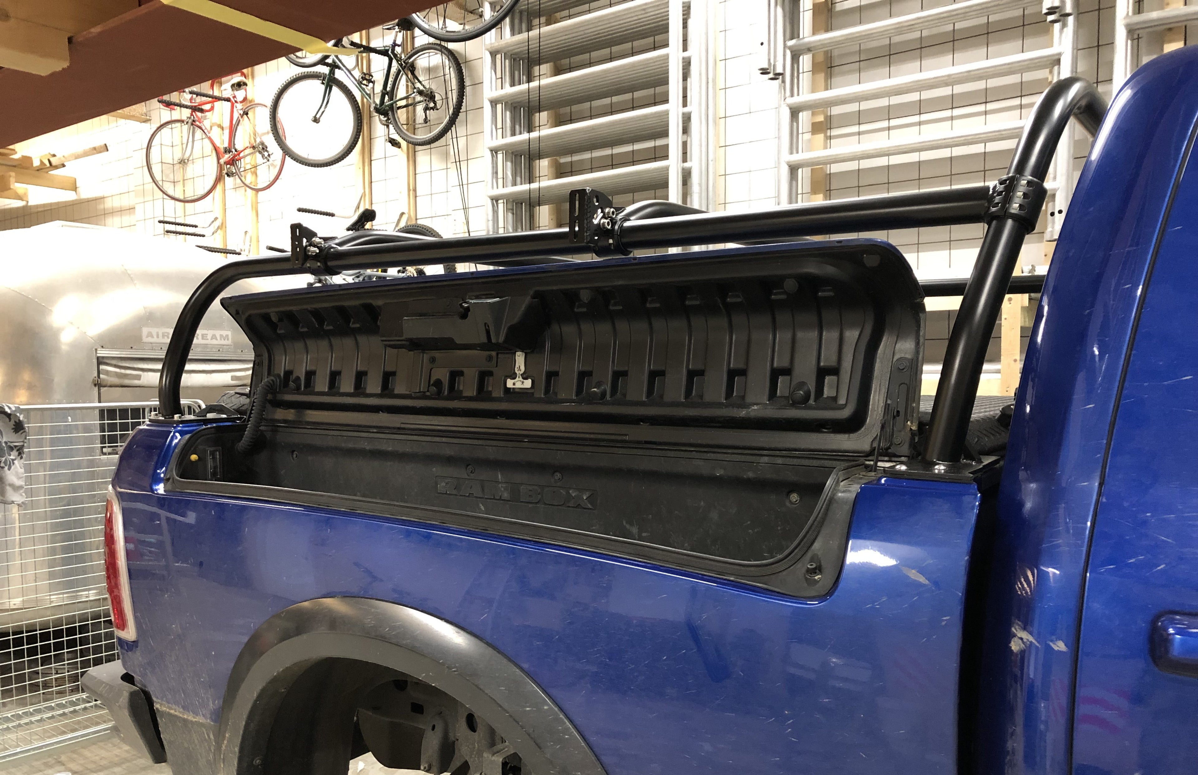 Rear quarter of the blue Ram with the tonneau folded up against the rack