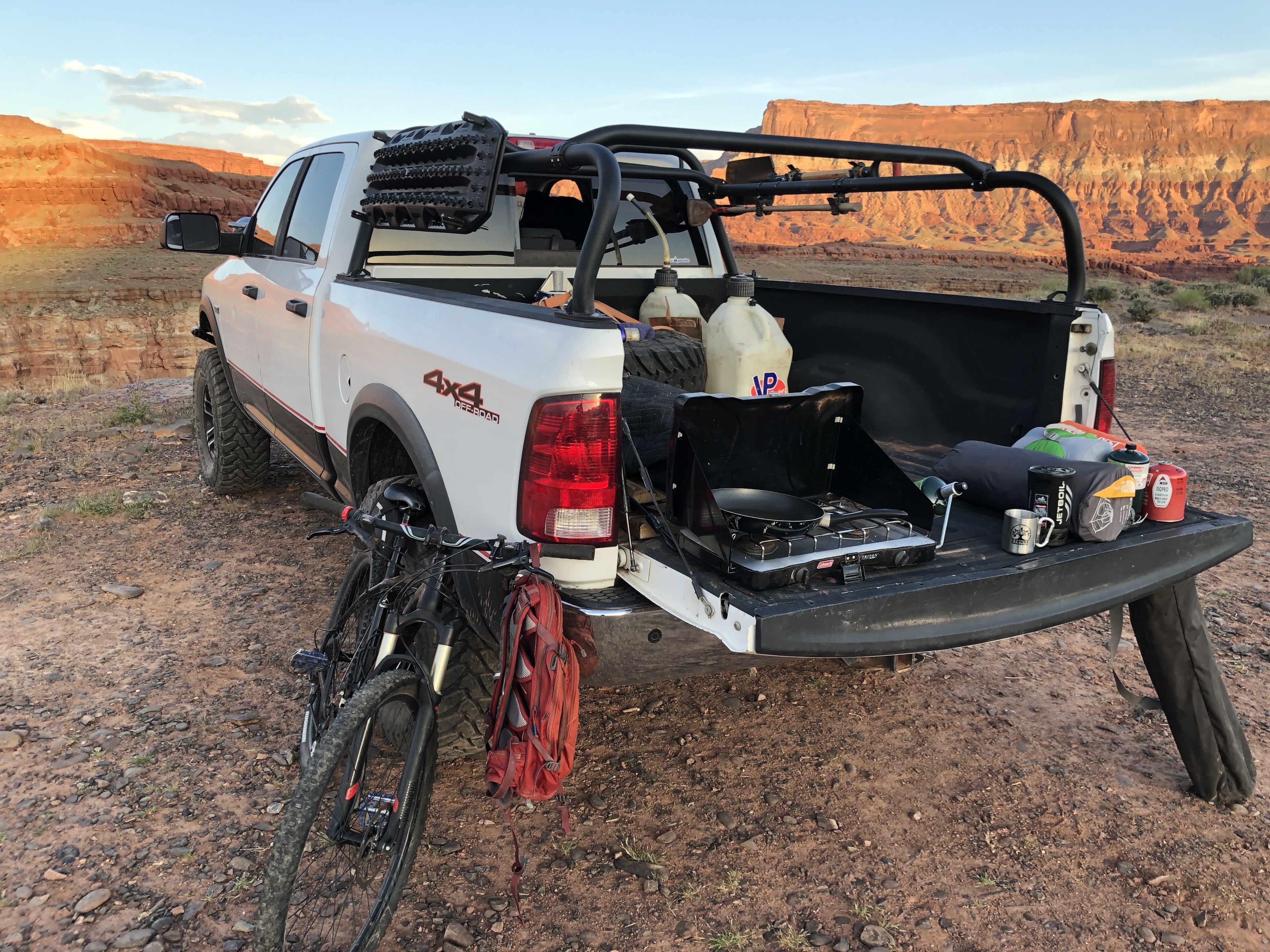 Tailgate down at a desert camp, the bed loaded with gear and the rack standing above it