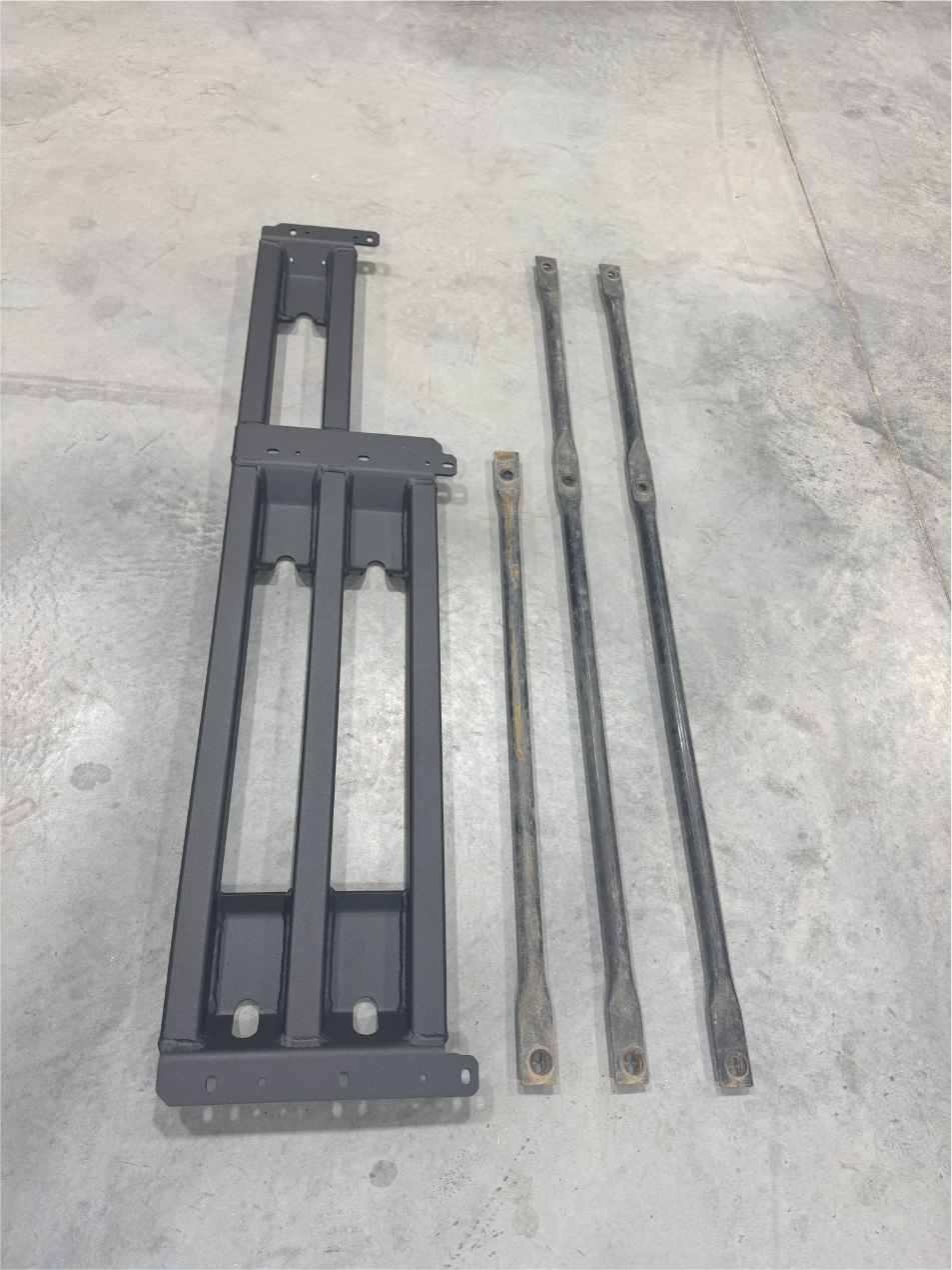 The same parts on the floor from another angle, bars alongside the frame