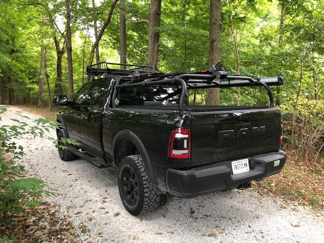 Rear quarter of a black Power Wagon on a gravel drive in the woods, bikes and a basket on the rack
