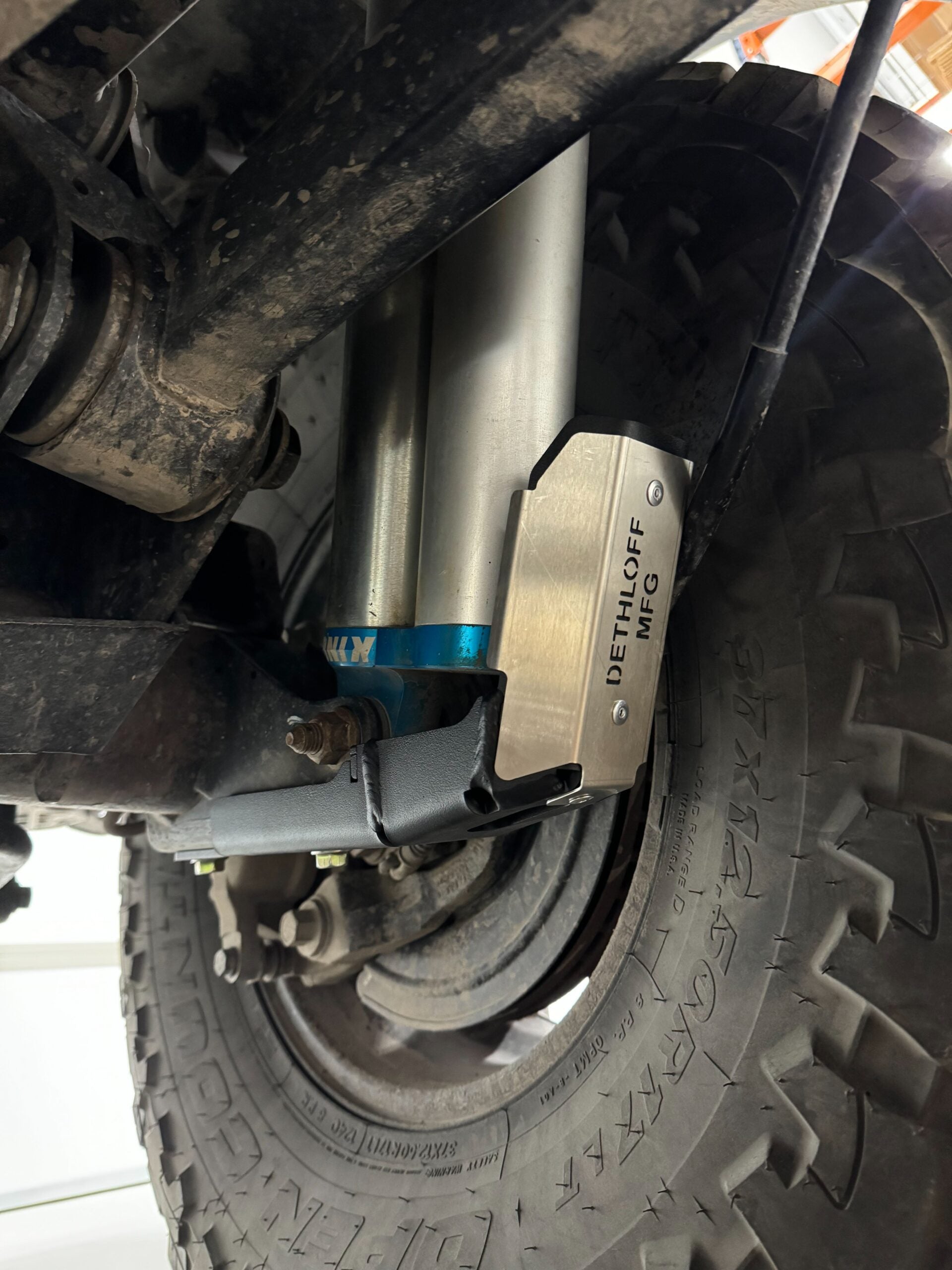 The guard bolted around a shock in the shop, badge visible above the blue shock body
