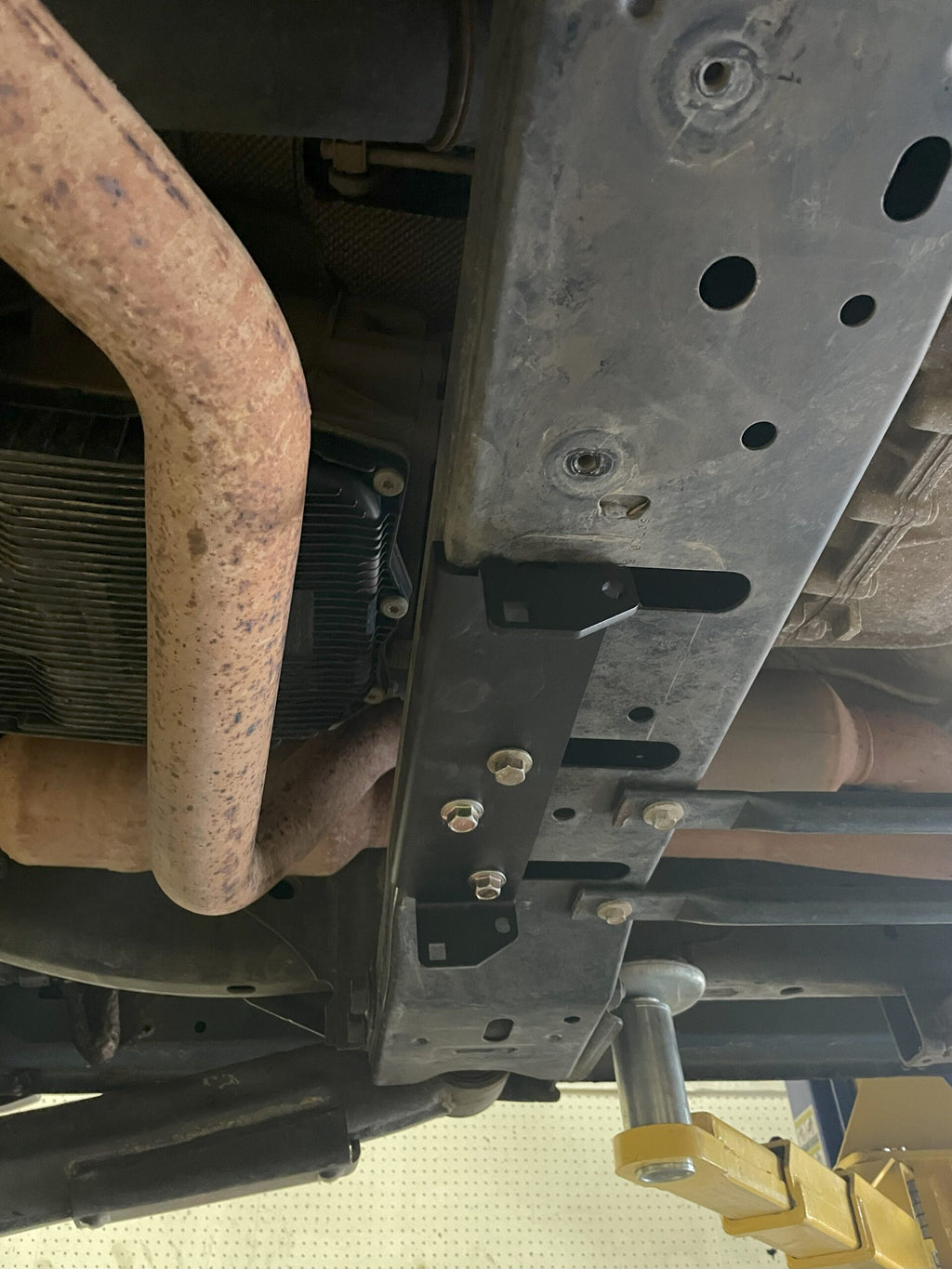 The edge of the plate under the truck beside the exhaust downpipe and cooler lines