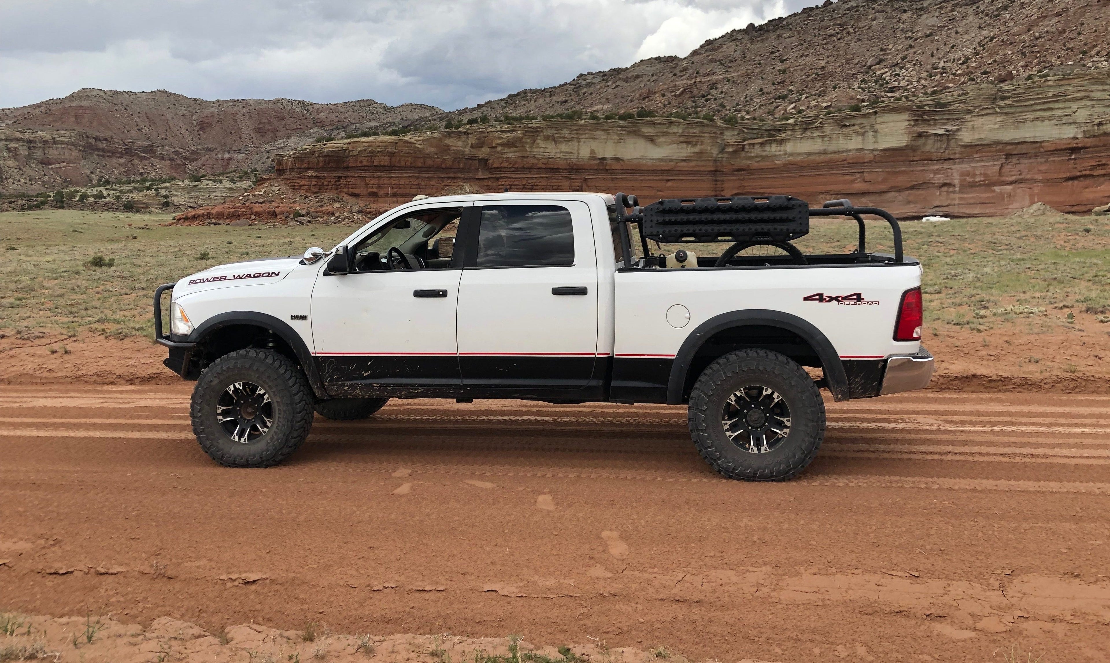 White Power Wagon on a red dirt road below sandstone cliffs, rack over the bed