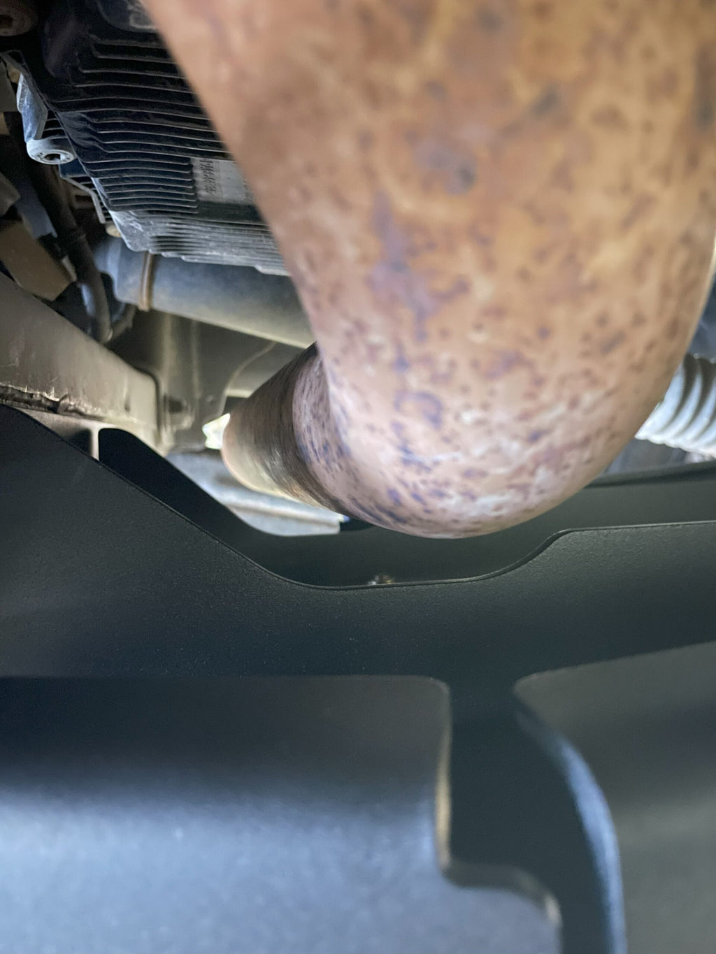 Close view under the truck where the plate passes beneath the exhaust pipe