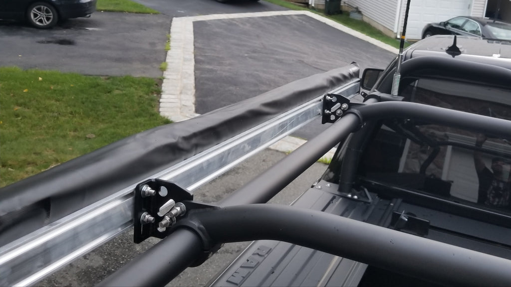 The awning rail bracketed to the rack bar above the bed, driveway beyond
