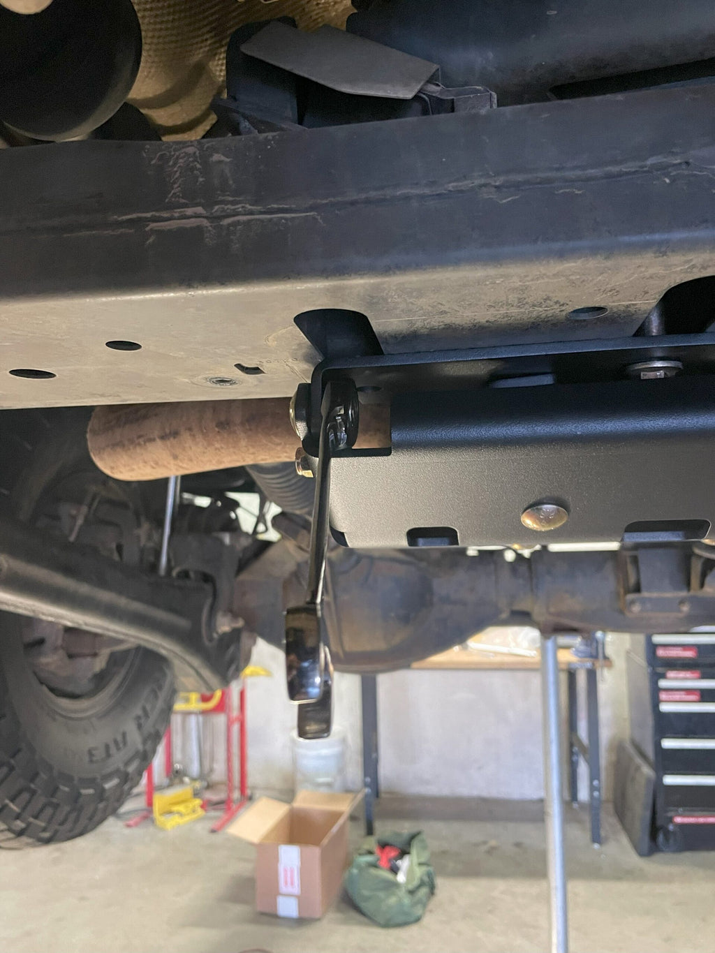 The full plate under the truck on a lift, seen from behind toward the front axle